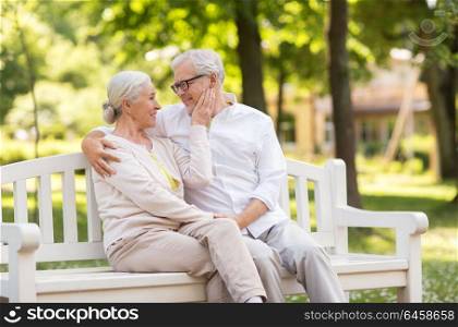 old age, relationship and people concept - happy senior couple sitting on bench at summer park. happy senior couple sitting on bench at park