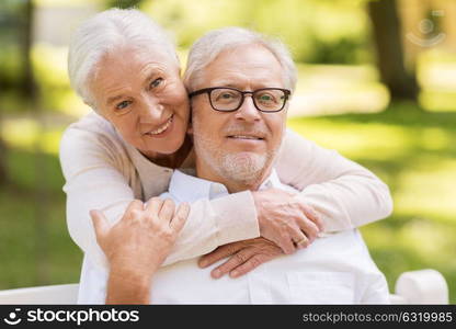 old age, relationship and people concept - portrait of happy senior couple hugging at summer park. portrait of happy senior couple at park