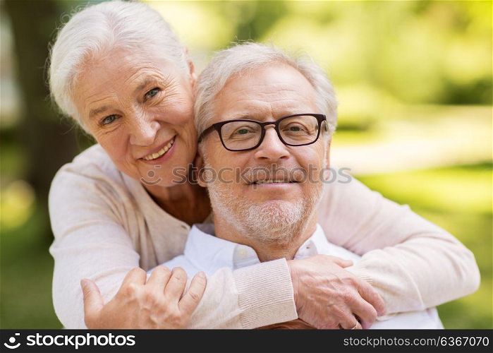 old age, relationship and people concept - portrait of happy senior couple hugging at summer park. portrait of happy senior couple at park