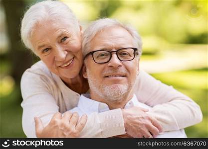 old age, relationship and people concept - portrait of happy senior couple hugging at summer park. portrait of happy senior couple at park