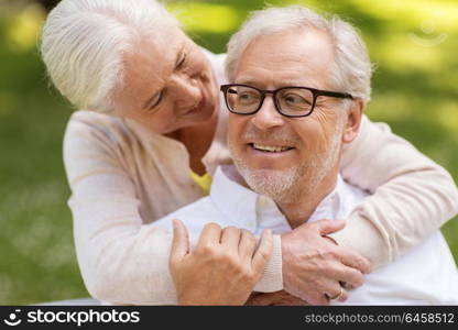 old age, relationship and people concept - portrait of happy senior couple hugging at summer park. portrait of happy senior couple at park