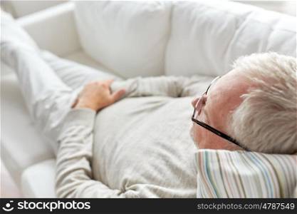 old age, rest, comfort and people concept - close up of senior man lying on sofa