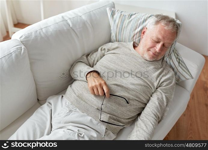old age, rest, comfort and people concept - senior man sleeping on sofa at home