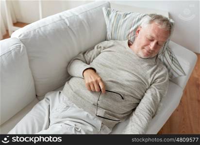 old age, rest, comfort and people concept - senior man sleeping on sofa at home