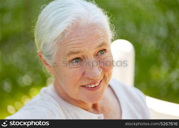 old age, retirement and people concept - close up of happy senior woman in glasses sitting on bench at summer park. happy senior woman sitting on bench at summer park