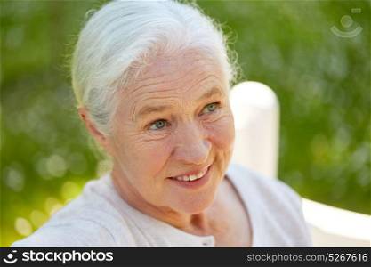 old age, retirement and people concept - close up of happy senior woman in glasses sitting on bench at summer park. happy senior woman sitting on bench at summer park