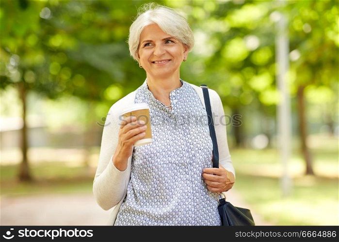 old age, retirement and people concept - close up of happy senior woman drinking takeaway coffee at summer park. senior woman drinking takeaway coffee at park