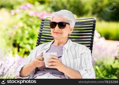 old age, retirement and people concept - close up of happy senior woman drinking coffee or tea at summer garden. happy senior woman drinking coffee at garden