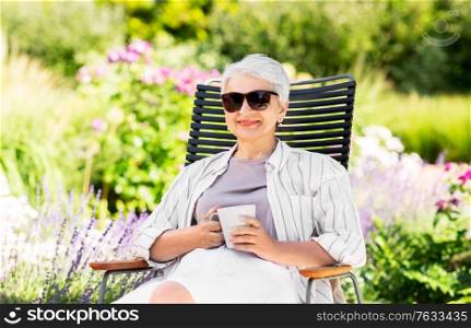 old age, retirement and people concept - close up of happy senior woman drinking coffee or tea at summer garden. happy senior woman drinking coffee at garden