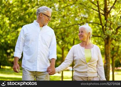 old age, retirement and people concept - happy senior couple holding hands and walking at summer park. happy senior couple walking at summer park