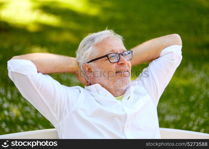 old age, retirement and people concept - happy senior man in glasses sitting and relaxing outdoors. happy senior man in glasses sitting at summer park