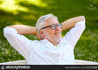 old age, retirement and people concept - happy senior man in glasses sitting and relaxing outdoors. happy senior man in glasses sitting at summer park
