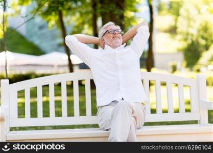 old age, retirement and people concept - happy senior man sitting on bench at summer park. happy senior man sitting on bench at summer park