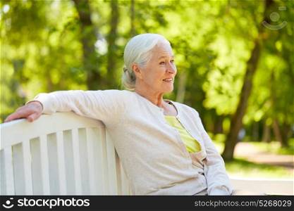 old age, retirement and people concept - happy senior woman in glasses sitting on bench at summer park. happy senior woman sitting on bench at summer park