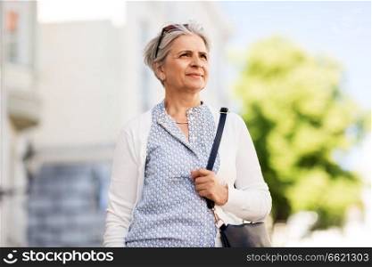 old age, retirement and people concept - happy senior woman with handbag on city street in summer. happy senior woman on city street in summer
