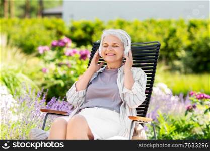 old age, retirement and people concept - happy senior woman with headphones listening to music at summer garden. happy senior woman with headphones at garden