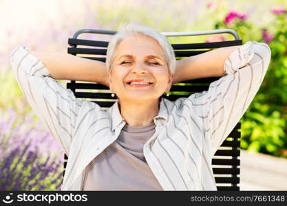 old age, retirement and people concept - happy smiling senior woman resting on chair at summer garden. happy senior woman resting at summer garden