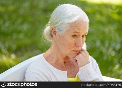 old age, retirement and people concept - sad senior woman in glasses sitting on bench at summer park. sad senior woman sitting on bench at summer park