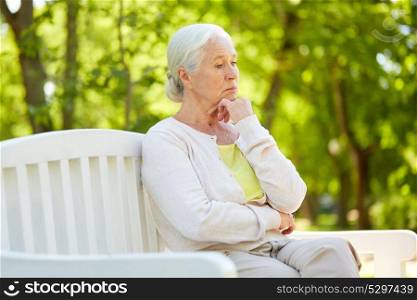 old age, retirement and people concept - sad senior woman in glasses sitting on bench at summer park. sad senior woman sitting on bench at summer park