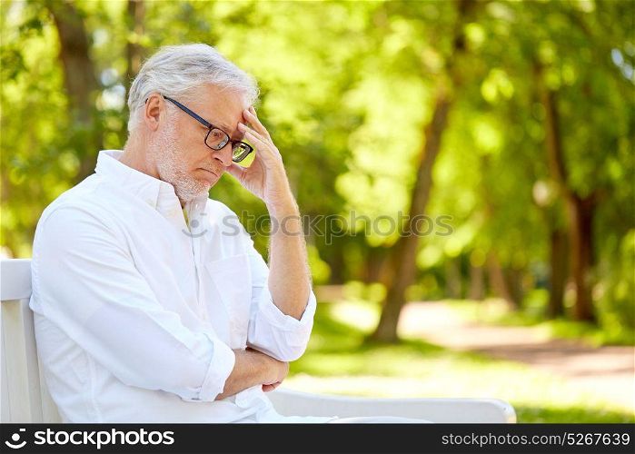 old age, retirement and people concept - thoughtful senior man in glasses sitting on bench at summer park. thoughtful senior man sitting at summer park