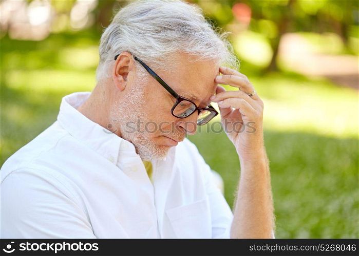old age, retirement and people concept - thoughtful senior man in glasses at summer park. thoughtful senior man at summer park