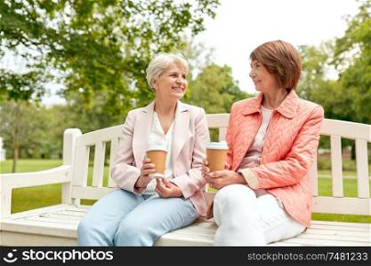 old age, retirement and people concept - two senior women or friends drinking coffee and talking at park. senior women or friends drinking coffee at park