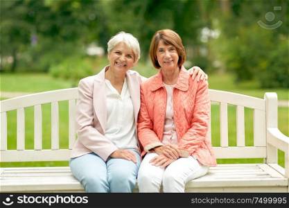 old age, retirement and people concept - two senior women or friends sitting on bench at summer park. senior women or friends sitting on bench at park