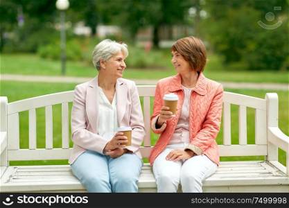 old age, retirement and people concept - two senior women or friends drinking coffee and talking at park. senior women or friends drinking coffee at park