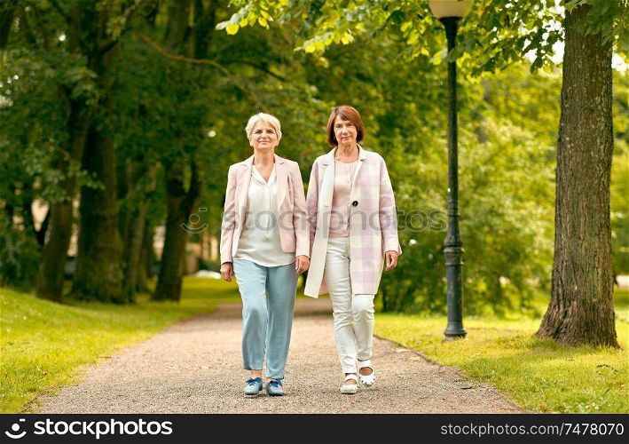 old age, retirement and people concept - two senior women or friends walking along summer park. senior women or friends walking along summer park