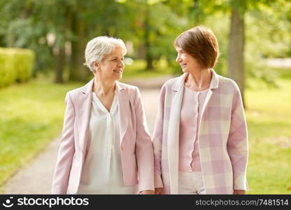 old age, retirement and people concept - two senior women or friends walking along summer park. senior women or friends walking along summer park