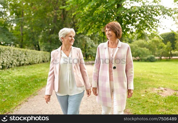 old age, retirement and people concept - two senior women or friends walking along summer park. senior women or friends walking along summer park