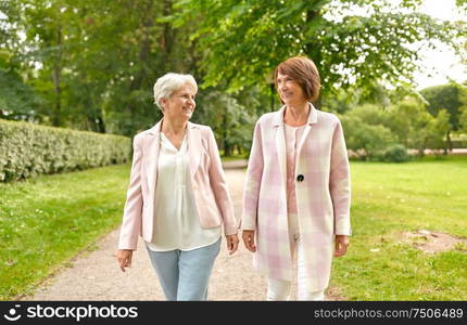 old age, retirement and people concept - two senior women or friends walking along summer park. senior women or friends walking along summer park