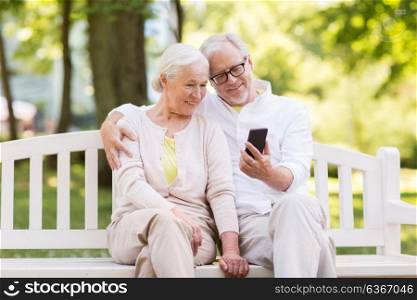 old age, technology and people concept - happy senior couple with smartphone at summer park. happy senior couple with smartphone at park