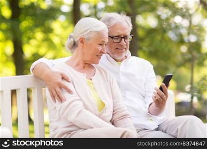 old age, technology and people concept - happy senior couple with smartphone at summer park. happy senior couple with smartphone at park