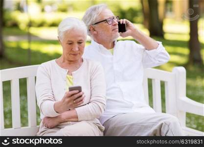 old age, technology and people concept - happy senior couple with smartphones at summer park. happy senior couple with smartphones at park