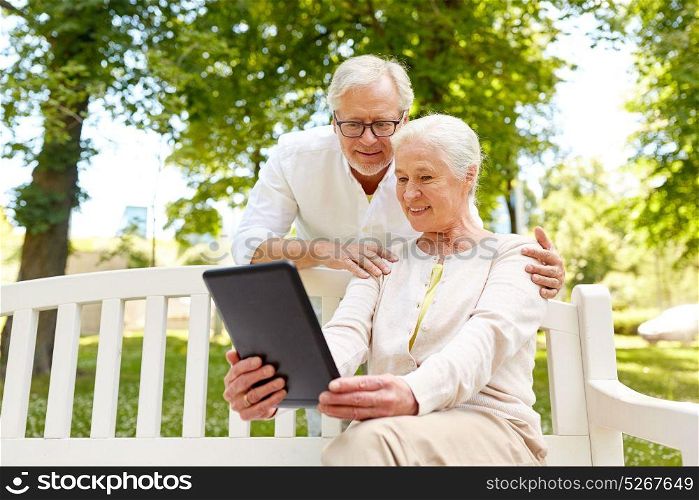 old age, technology and people concept - happy senior couple with tablet pc computer in city park. happy senior couple with tablet pc in city park