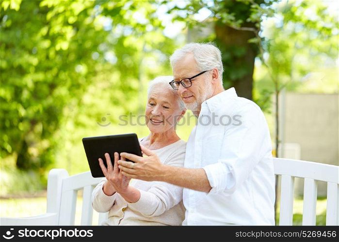 old age, technology and people concept - happy senior couple with tablet pc computer in city park. happy senior couple with tablet pc in city park