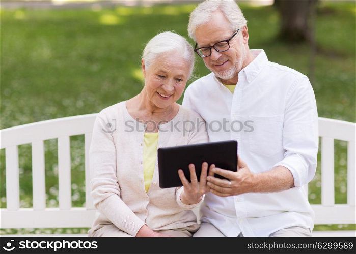 old age, technology and people concept - happy senior couple with tablet pc computer at summer park. happy senior couple with tablet pc at summer park