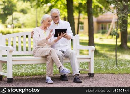 old age, technology and people concept - happy senior couple with tablet pc computer having video chat at summer park. senior couple with video chat on tablet pc at park