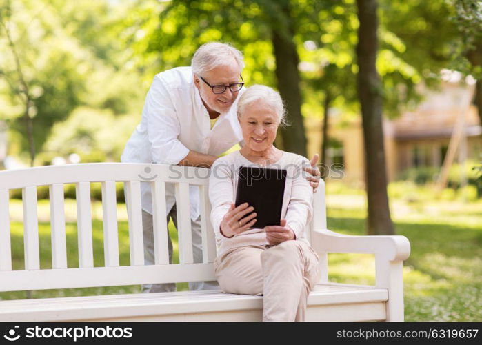 old age, technology and people concept - happy senior couple with tablet pc computer at summer park. happy senior couple with tablet pc at summer park