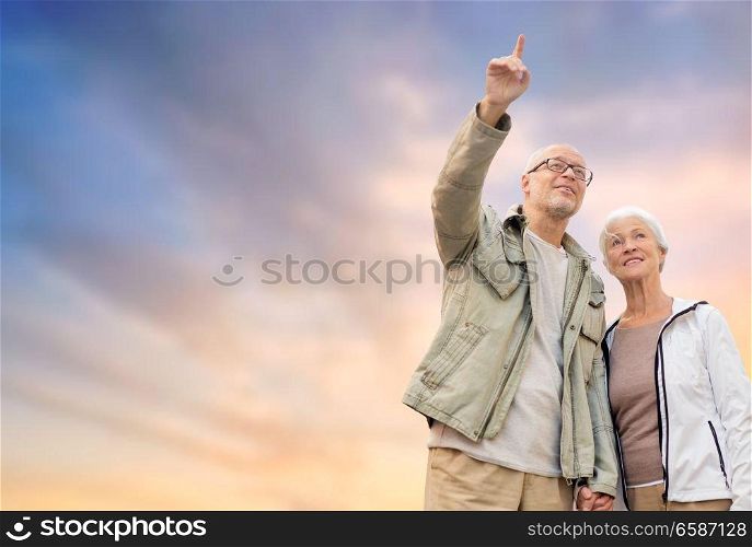 old age, tourism, travel and people concept - happy senior couple holding hands over evening sky background. happy senior couple holding hands over evening sky