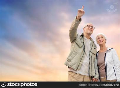 old age, tourism, travel and people concept - happy senior couple holding hands over evening sky background. happy senior couple holding hands over evening sky