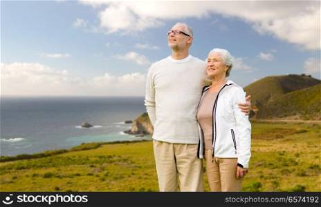 old age, tourism, travel and people concept - happy senior couple hugging over big sur coast of california background. happy senior couple hugging over big sur coast