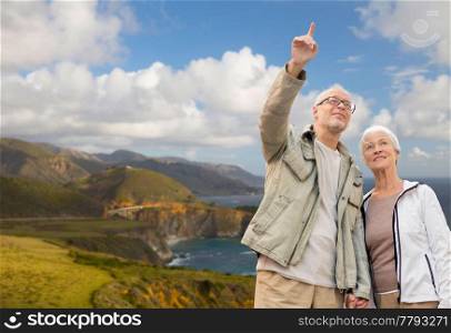 old age, tourism, travel and people concept - happy senior couple over bixby creek bridge on big sur coast of california background. happy senior couple over big sur coast