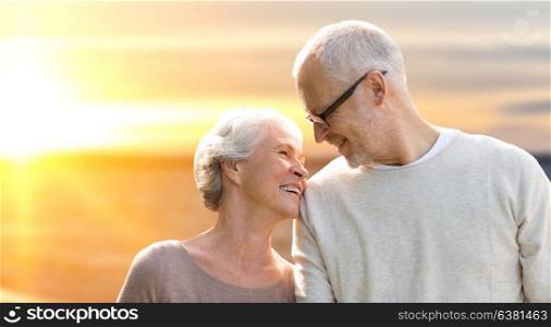 old age, tourism, travel and people concept - happy senior couple over sunset background. happy senior couple over sunset background