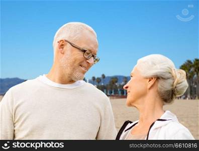 old age, travel and tourism and people concept - happy senior couple over venice beach background in california. happy senior couple over venice beach background