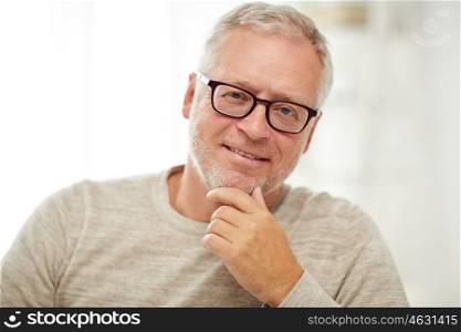 old age, vision and people concept - close up of smiling senior man in glasses thinking