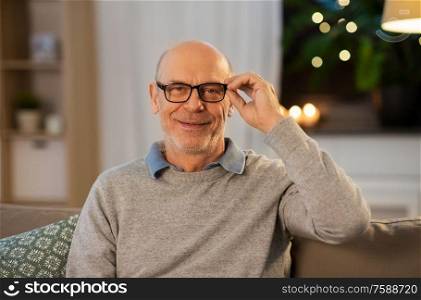 old age, vision, and people concept - happy smiling senior man in glasses at home in evening. happy smiling senior man in glasses at home
