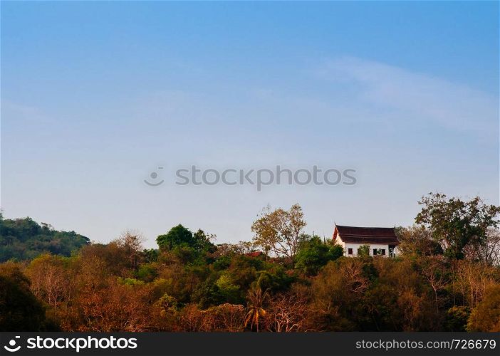 Old aged Buddhist church on mountain of Wat Chomphet Temple in Luang Prabang, Laos under blue sky in evening
