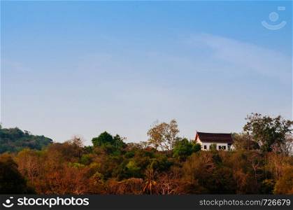 Old aged Buddhist church on mountain of Wat Chomphet Temple in Luang Prabang, Laos under blue sky in evening